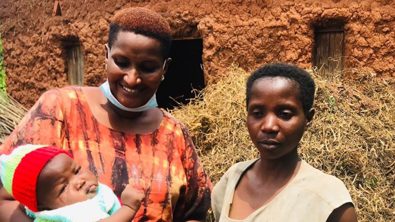 Two Rwandan women, one holding a baby and smiling.